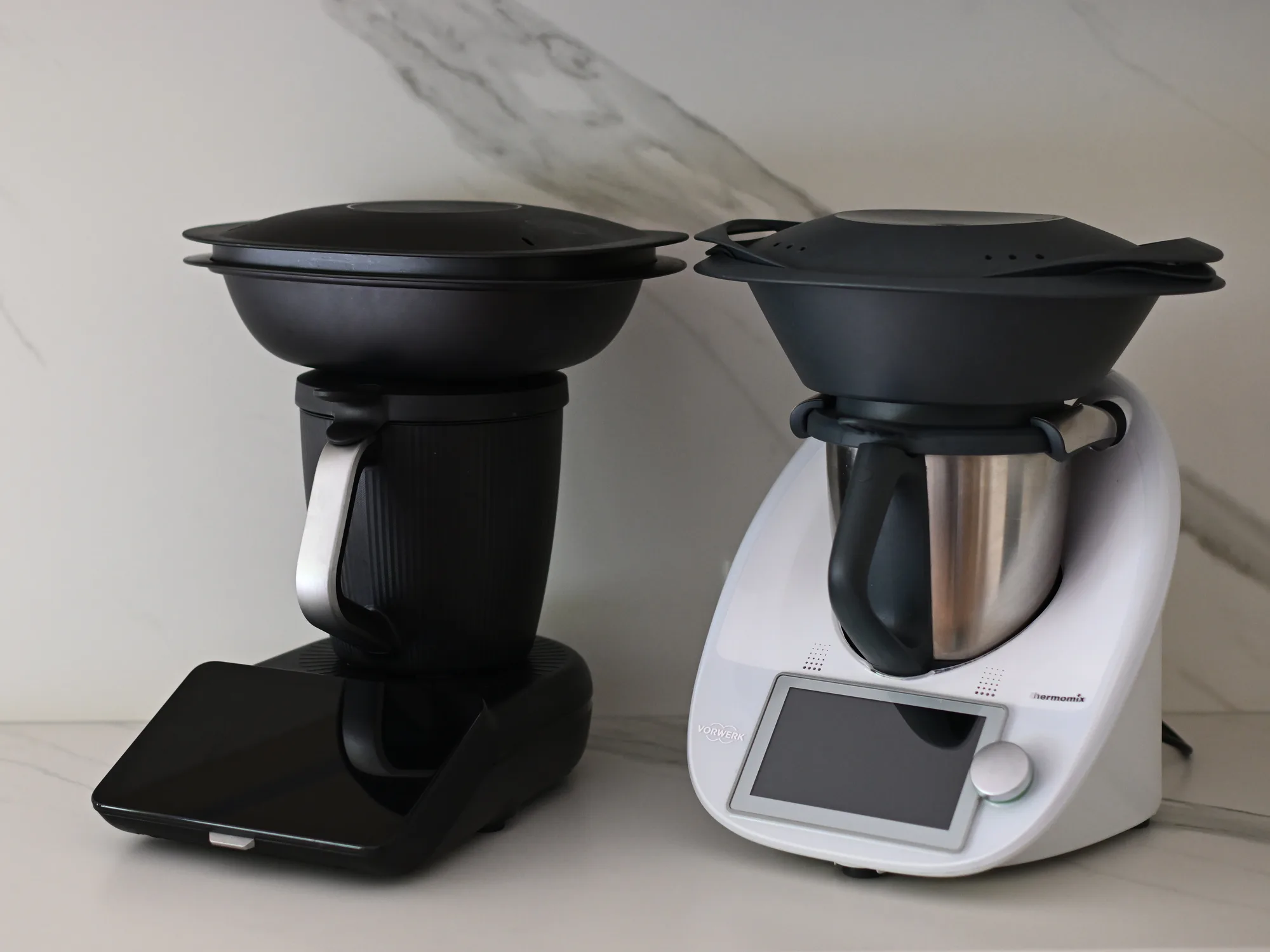 Thermomix TM6 w białej obudowie obok czarnego TM7, oba z Varomą